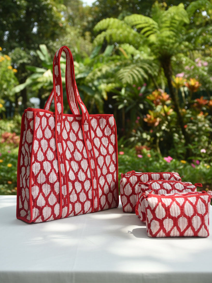 Red and white patterned tote bag on a bed with floral bedding
