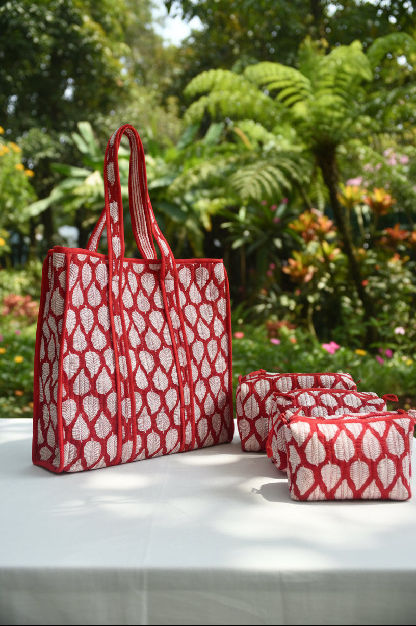 Red and white patterned tote bag on a bed with floral bedding