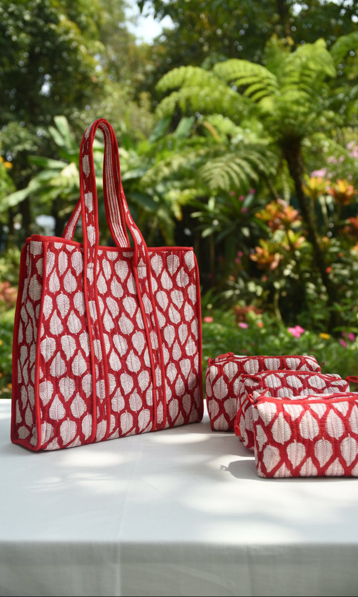 Red and white patterned tote bag on a bed with floral bedding