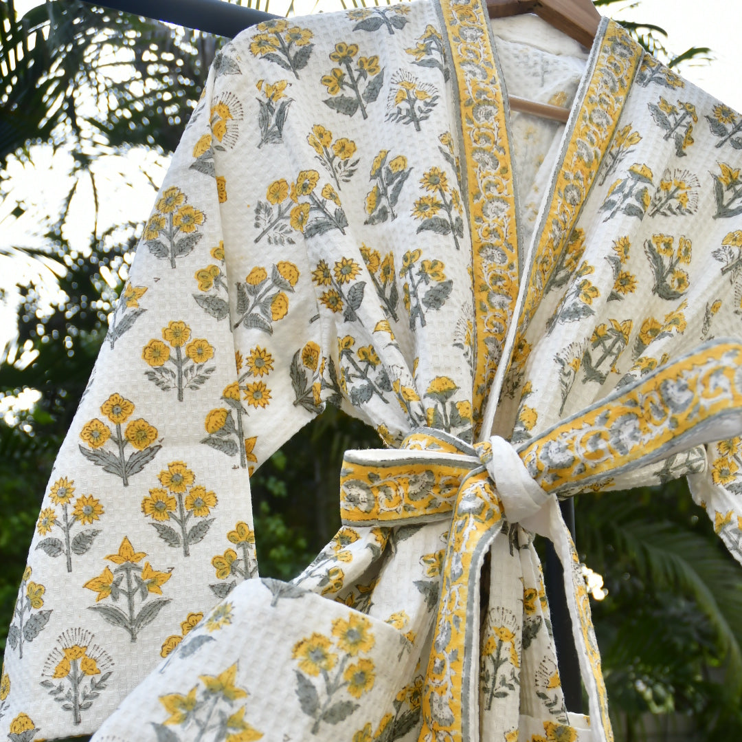 Floral-patterned fabric with yellow and gray flowers on a white background, tied together.