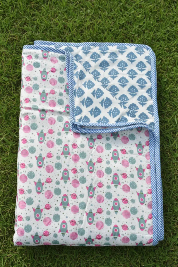 Two patterned blankets on a grassy surface