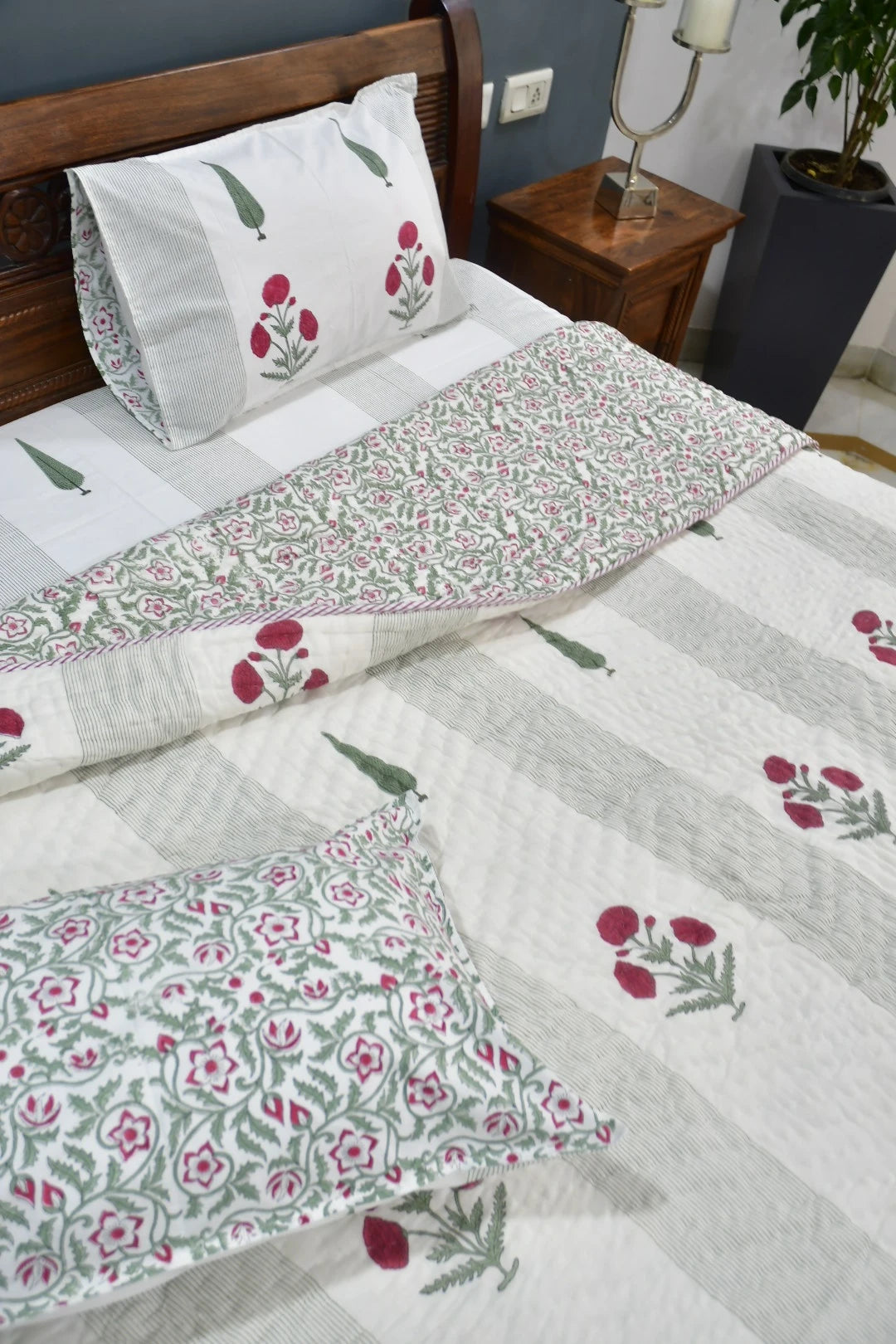 Floral patterned bedspread on a bed with matching pillows in a bedroom setting.