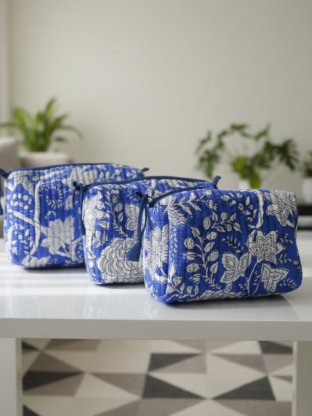 Set of three blue and white floral-patterned pouches on a dark surface with a neutral background