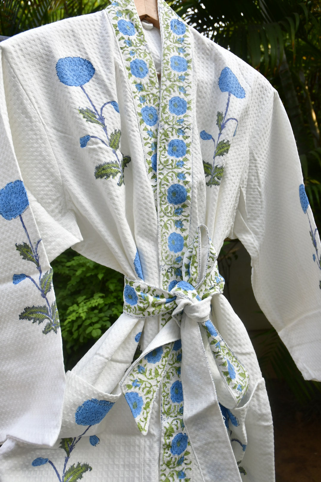 White fabric with blue floral patterns held by a person outdoors