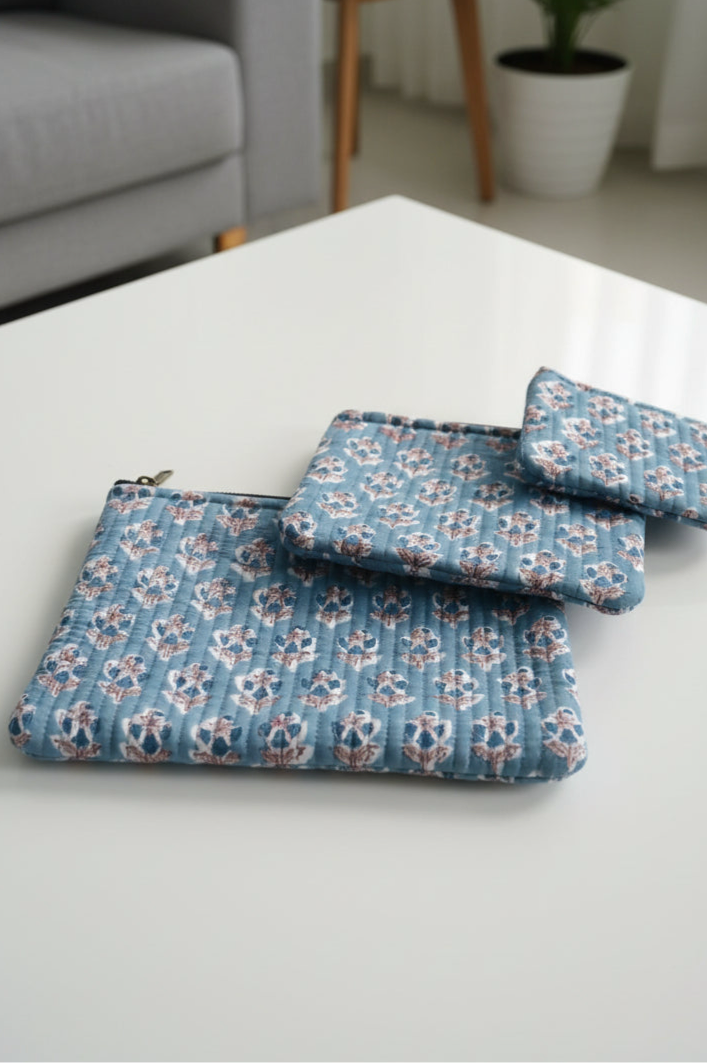 Set of blue floral-patterned pouches on a white surface with a blurred background