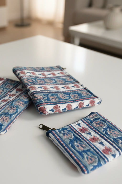 Two patterned pouches on a white surface with a blurred background