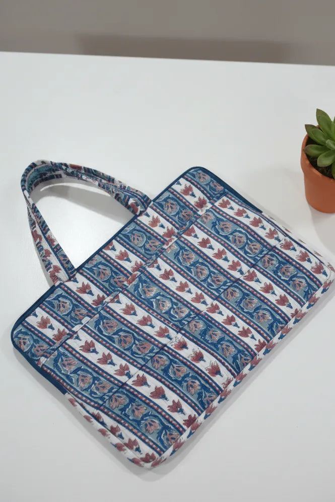 Blue and white patterned bag on a white surface with a small plant in the background