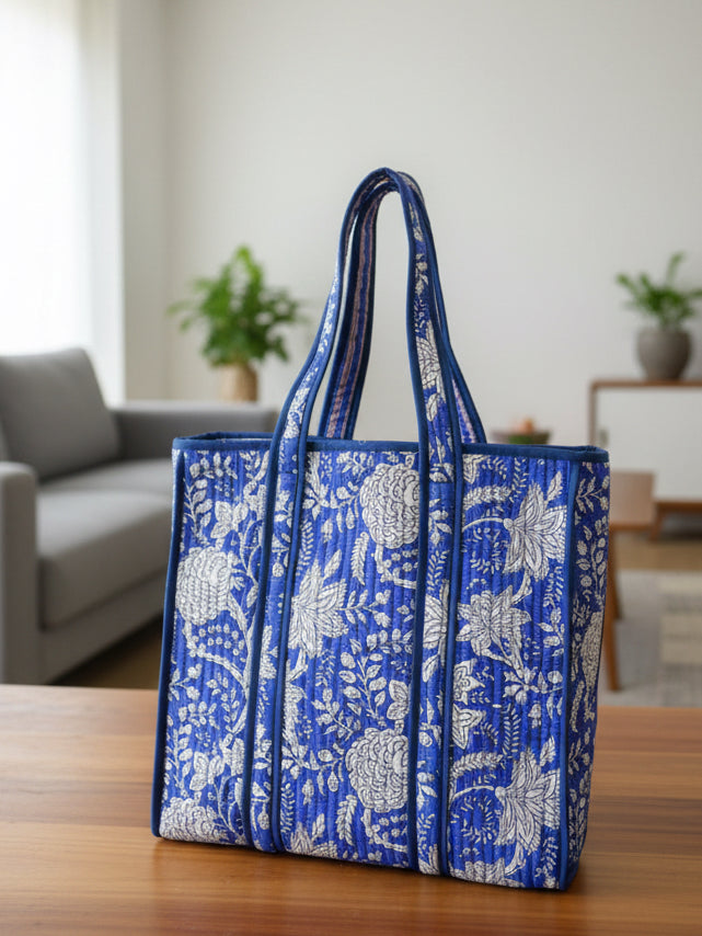 Blue and white floral patterned tote bag on a wooden surface with a blurred indoor background
