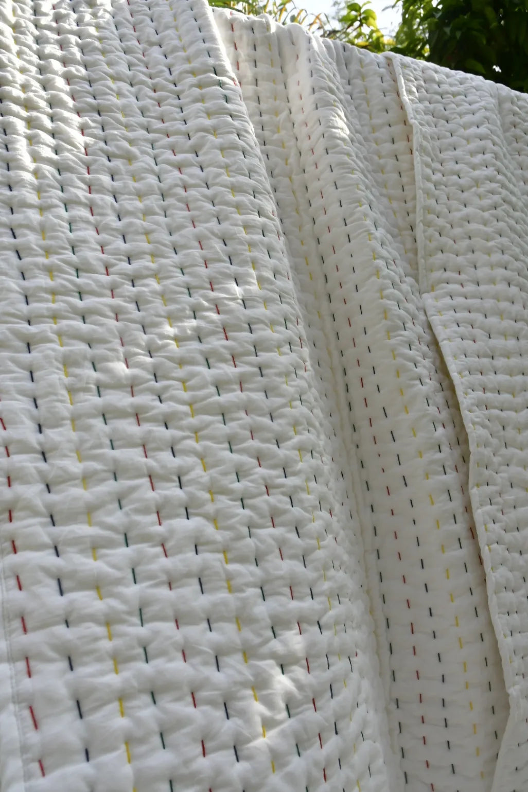Close-up of a textured white quilt with a subtle pattern.