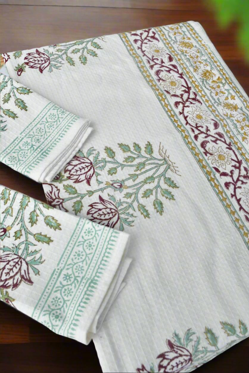 Set of tablecloth and napkins with floral patterns on a wooden surface
