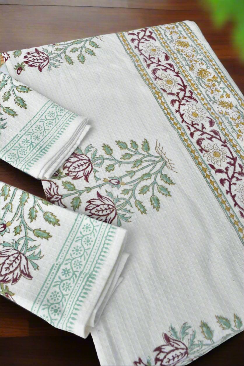 Set of tablecloth and napkins with floral patterns on a wooden surface