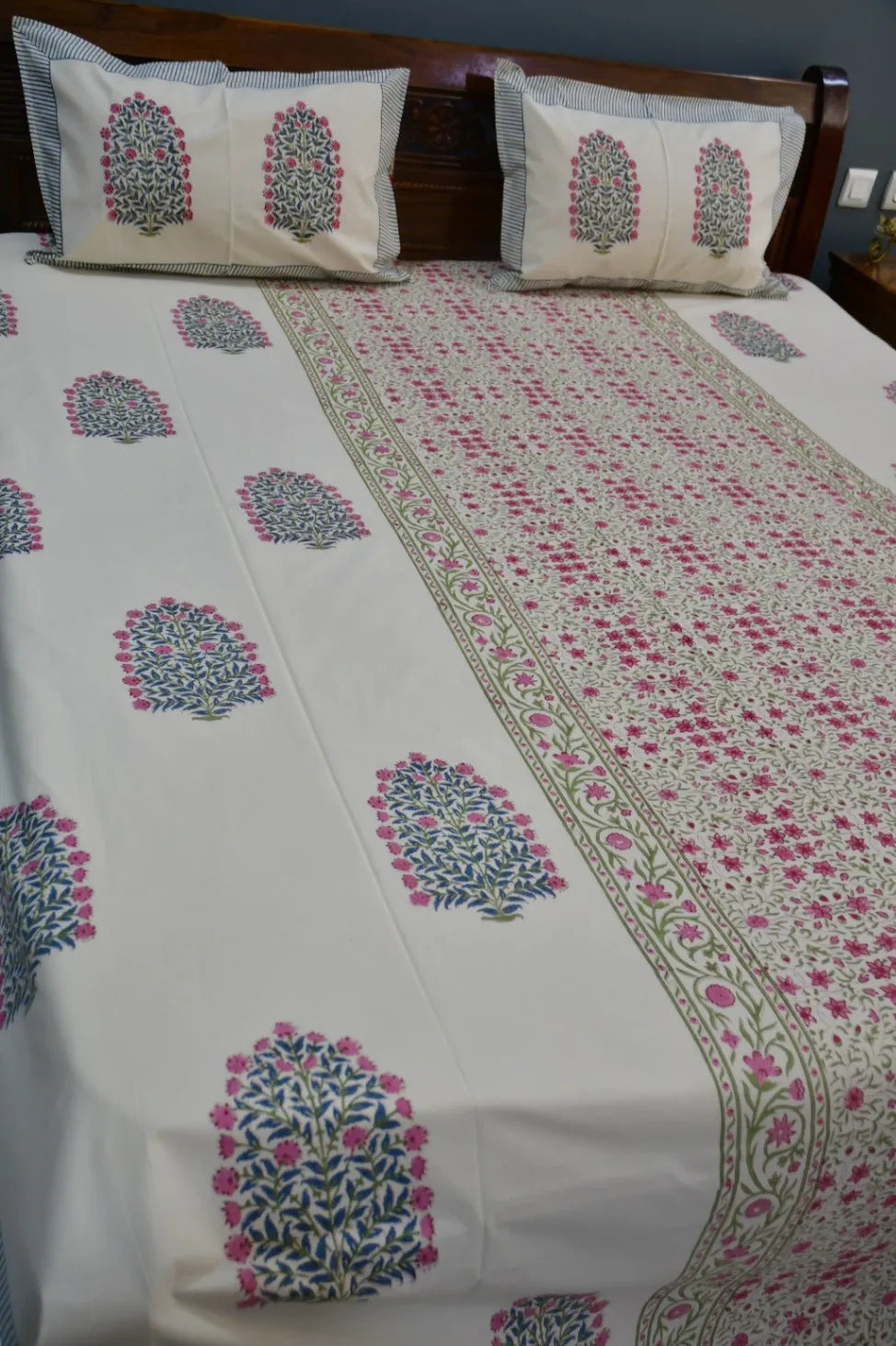 Floral patterned bedsheet on a bed with matching pillows.
