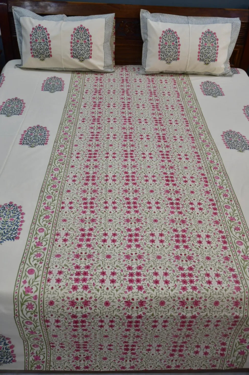 Floral patterned bedsheet on a bed with matching pillows.