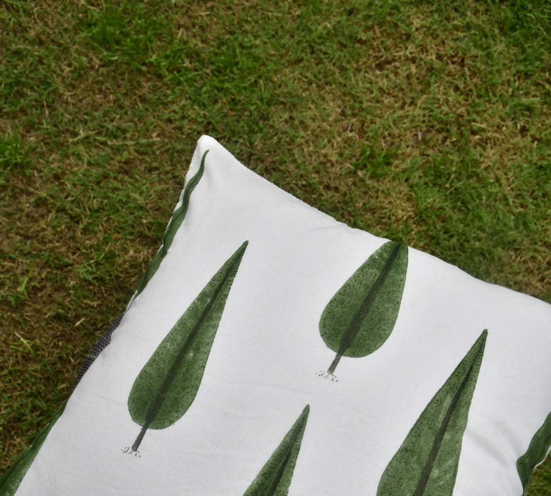 White pillow with green leaf patterns on a grassy background