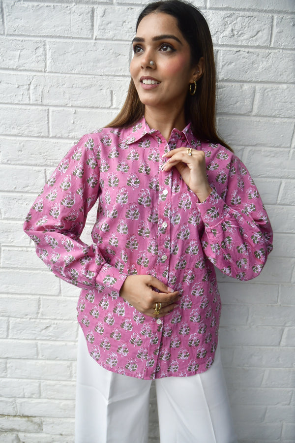 Woman wearing a pink floral blouse on a white brick wall background