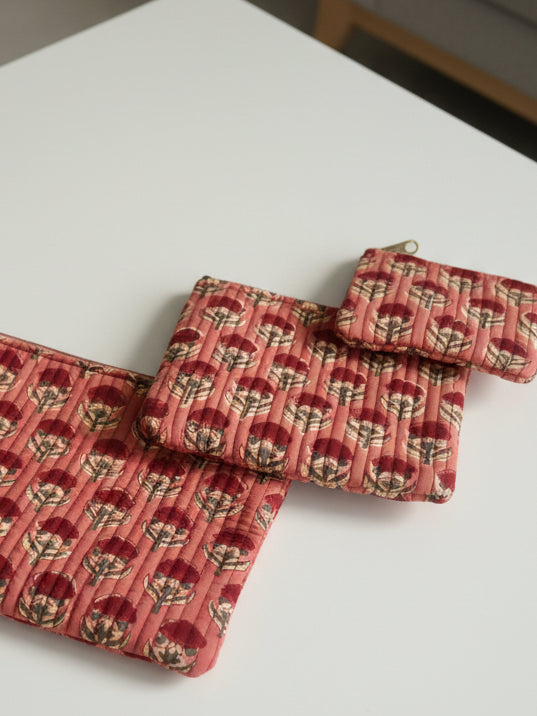 Two red patterned pouches on a white surface