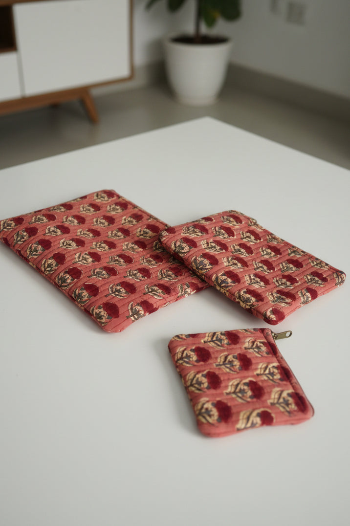 Three red patterned coasters on a floral tablecloth