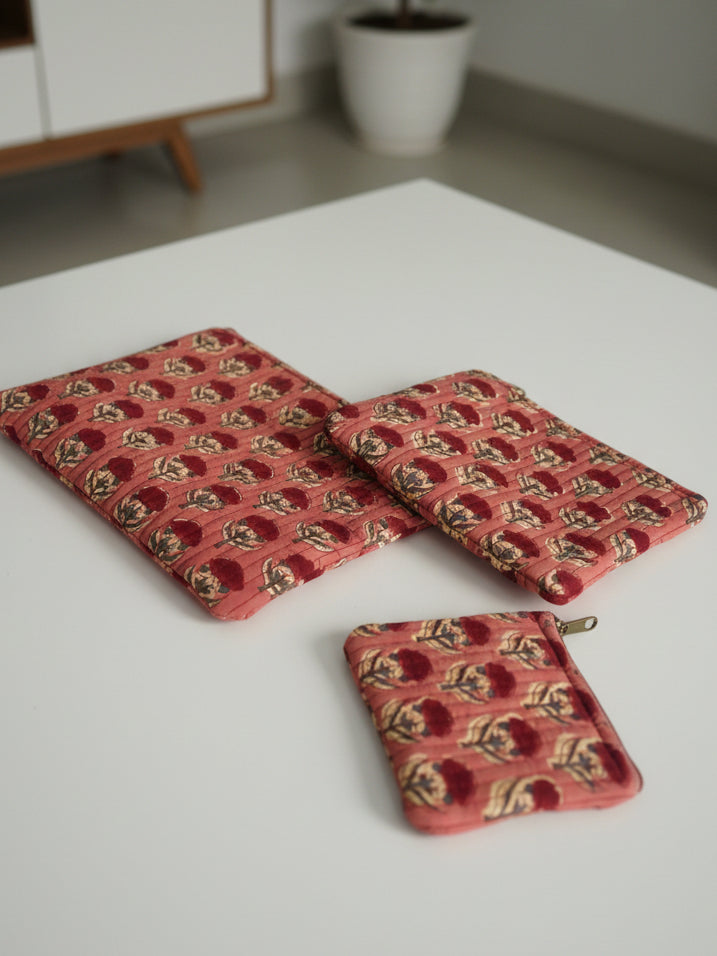 Three red patterned coasters on a floral tablecloth
