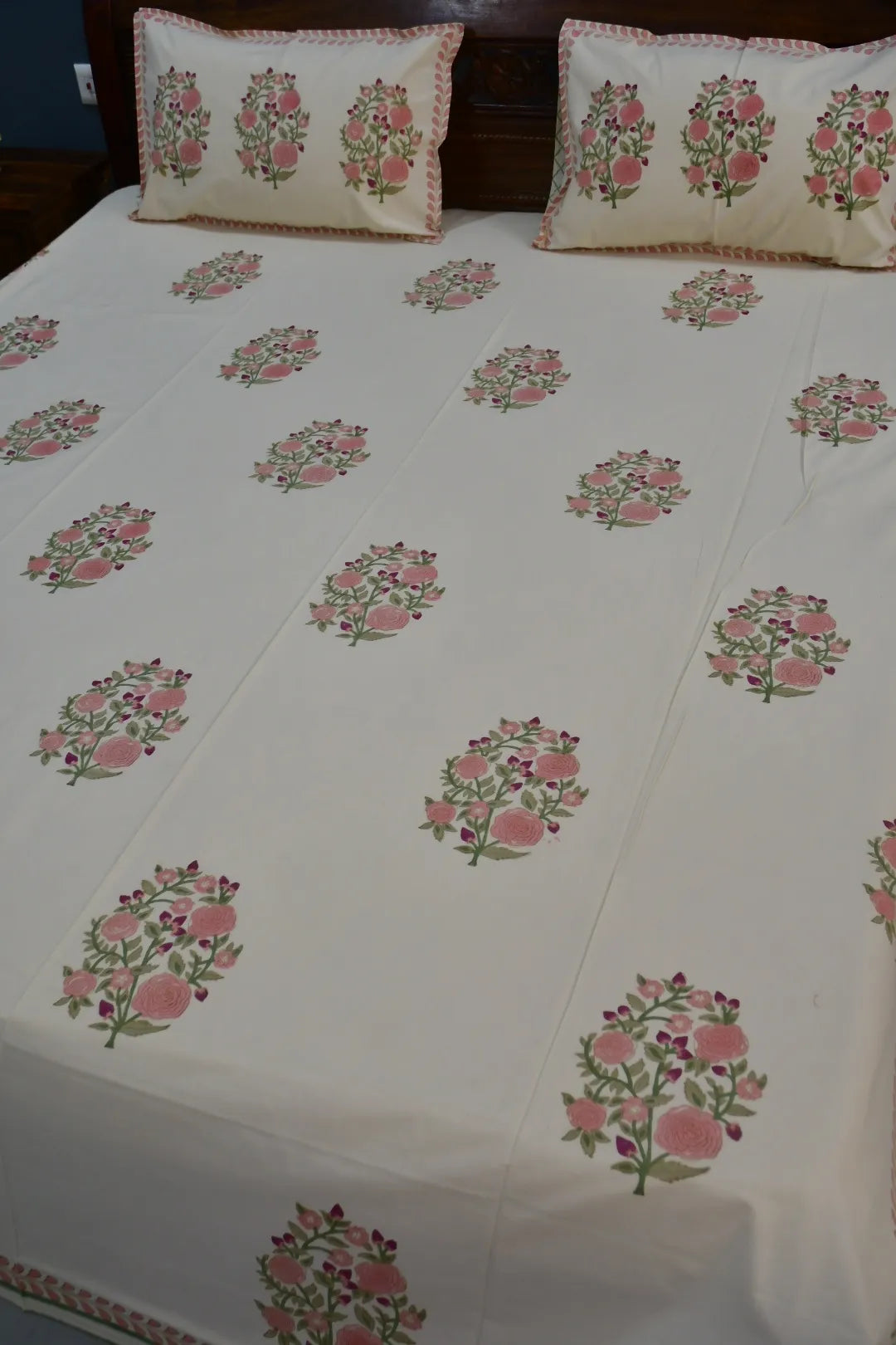 Floral patterned bedspread on a bed with matching pillows.