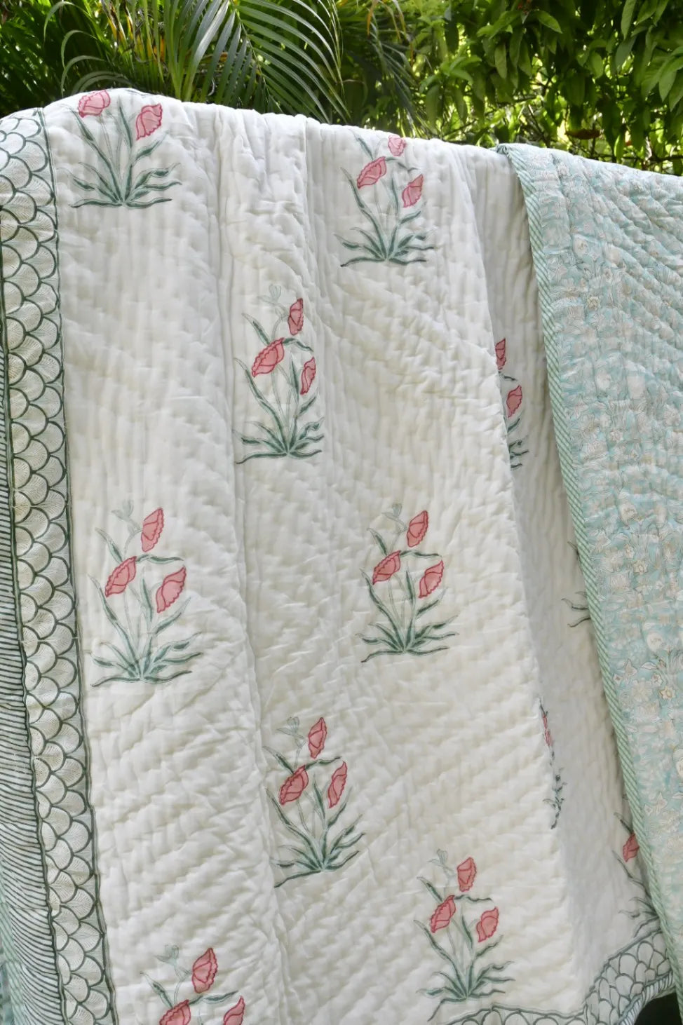 Floral quilt with pink flowers on a green leafy background