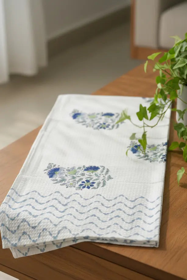 Floral-patterned towel on a wooden surface with a plant in the background