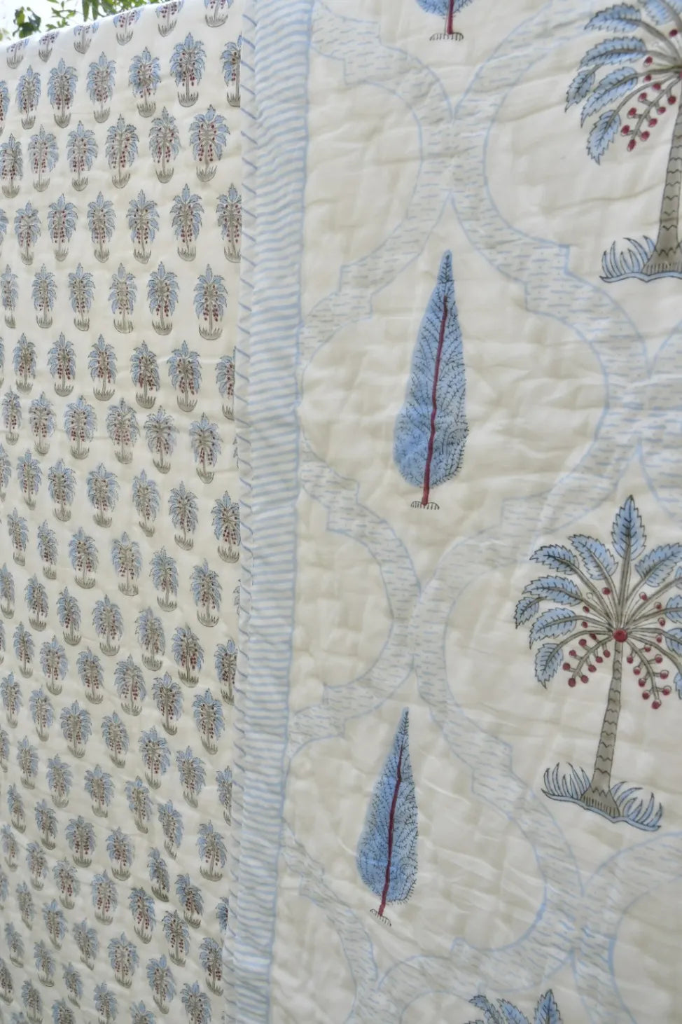 Close-up of a quilt with embroidered palm trees and patterns on a beige background