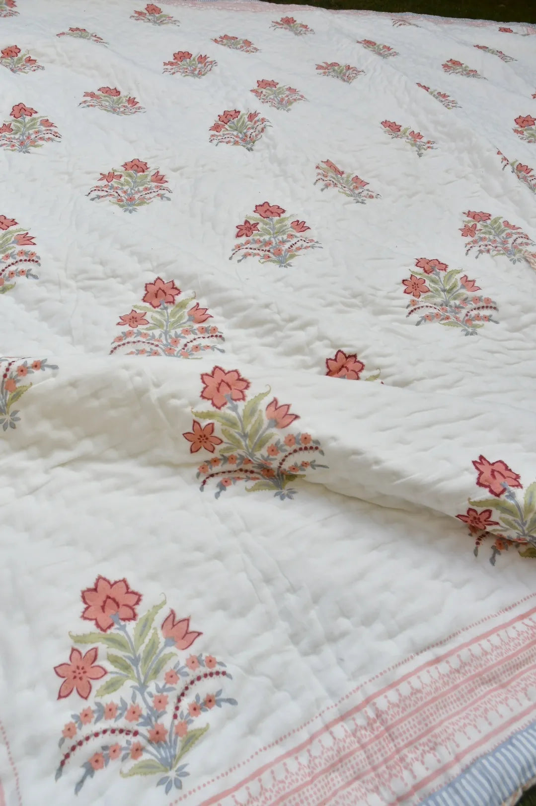 Floral patterned quilt with pink and green flowers on a white background