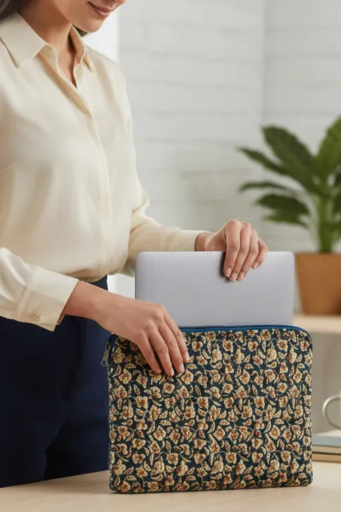 Person holding a floral laptop sleeve with a laptop inside, in an indoor setting.