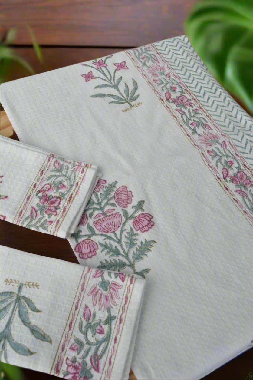 Set of floral patterned napkins on a wooden surface with greenery in the background