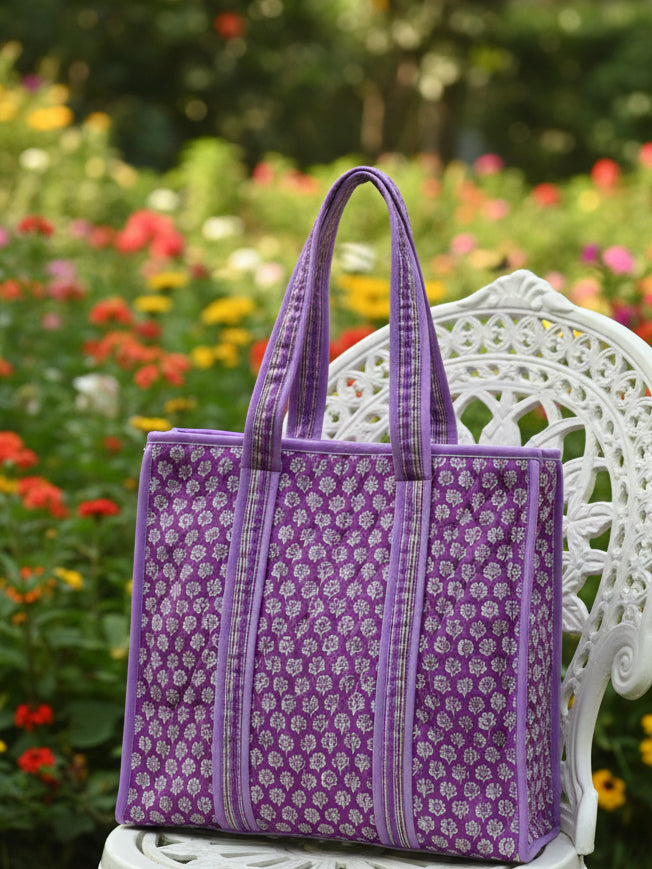 Purple patterned bag on a bed with a neutral background