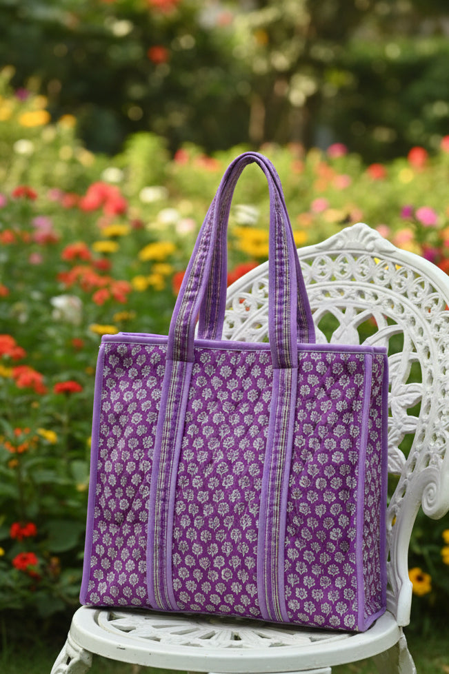 Purple patterned bag on a bed with a neutral background