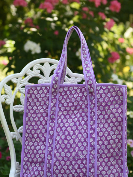 Purple floral-patterned bag on a gray surface with a white background