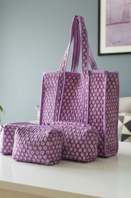 Purple patterned tote bag and pouch on a white surface with a light blue wall in the background.