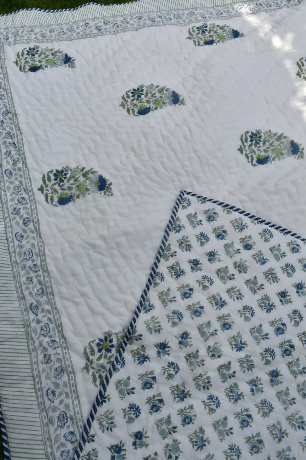 Quilt with floral patterns in blue and green on a white background