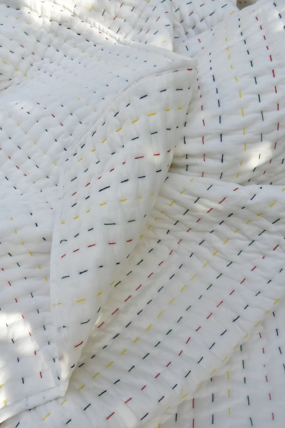 Close-up of white Kantha quilt with colorful thread patterns