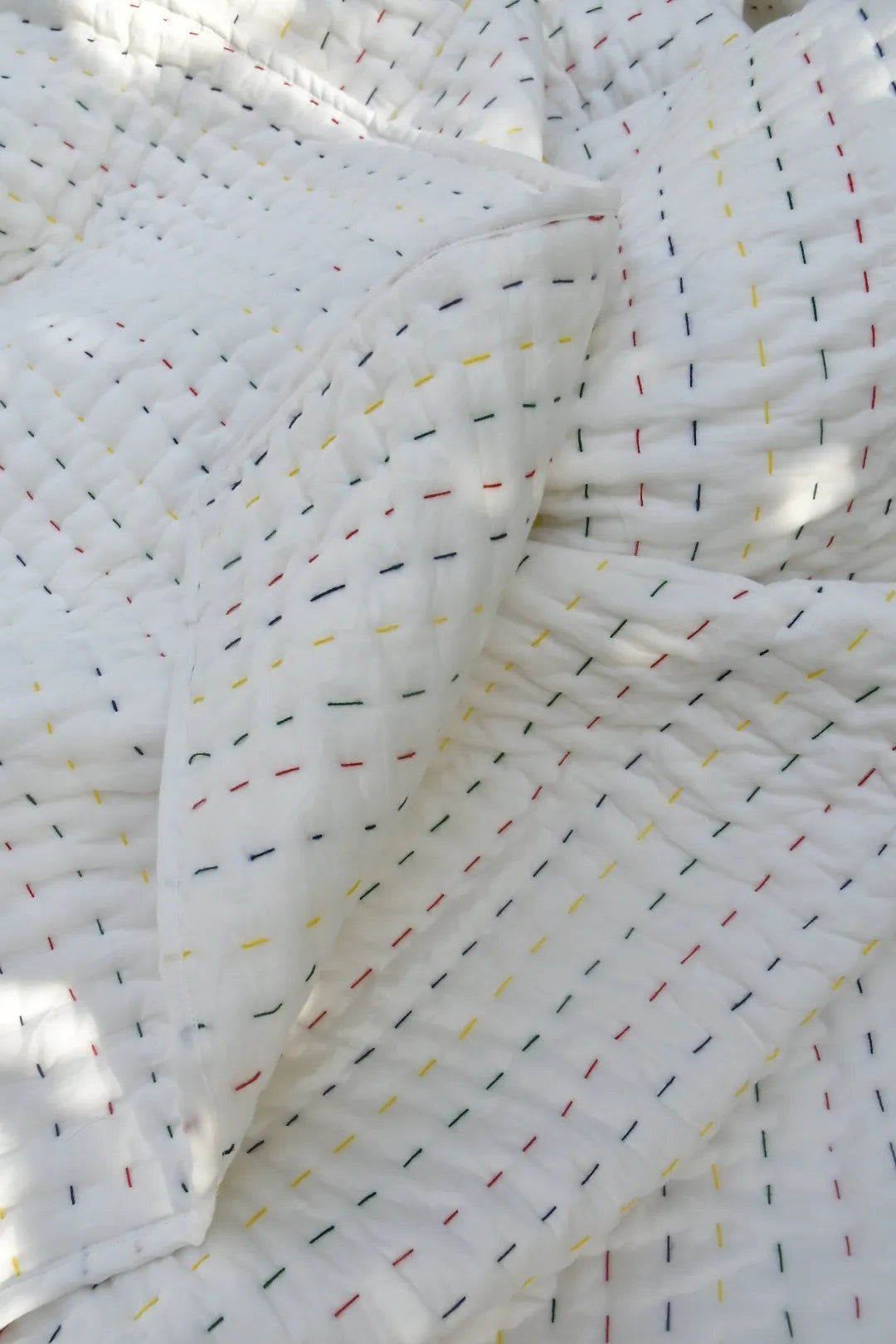 Close-up of white Kantha quilt with colorful thread patterns