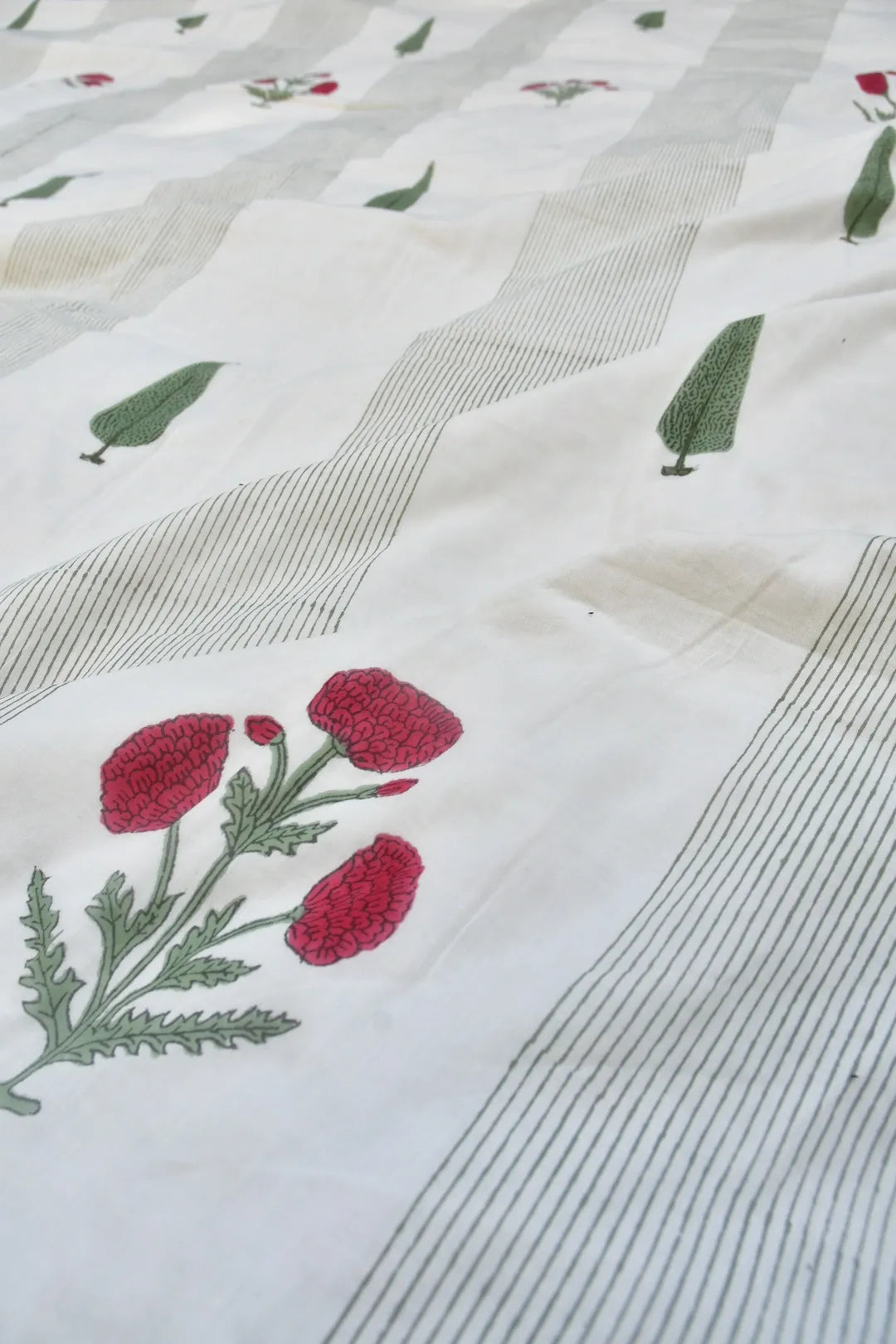 Embroidered fabric with red flowers and green leaves on a white background