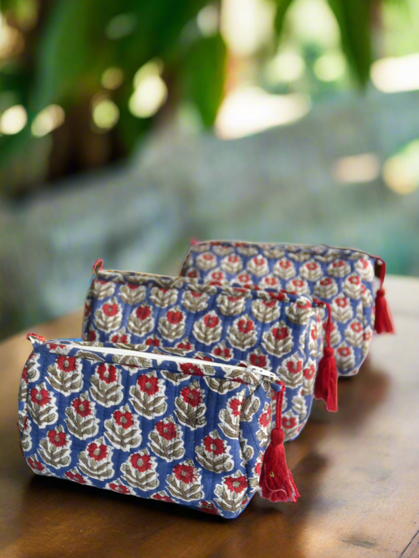 Two floral-patterned pouches with red accents on a wooden surface with a blurred natural background