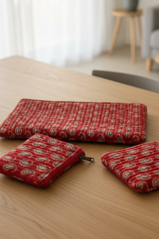 Three red patterned pouches on a floral fabric background