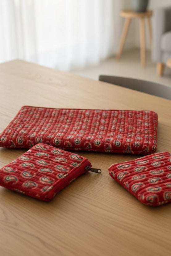 Three red patterned pouches on a floral fabric background