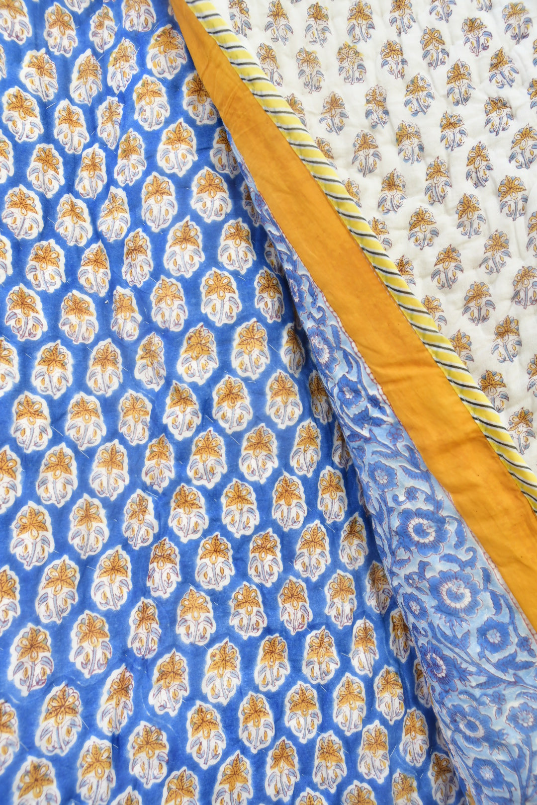 Hand-blocked Royal Blue and Yellow Floral Buta Jaipuri Razai on a single bed