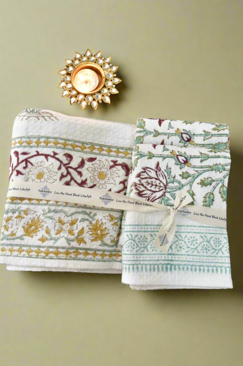 Two patterned towels on a green surface with a decorative candle.