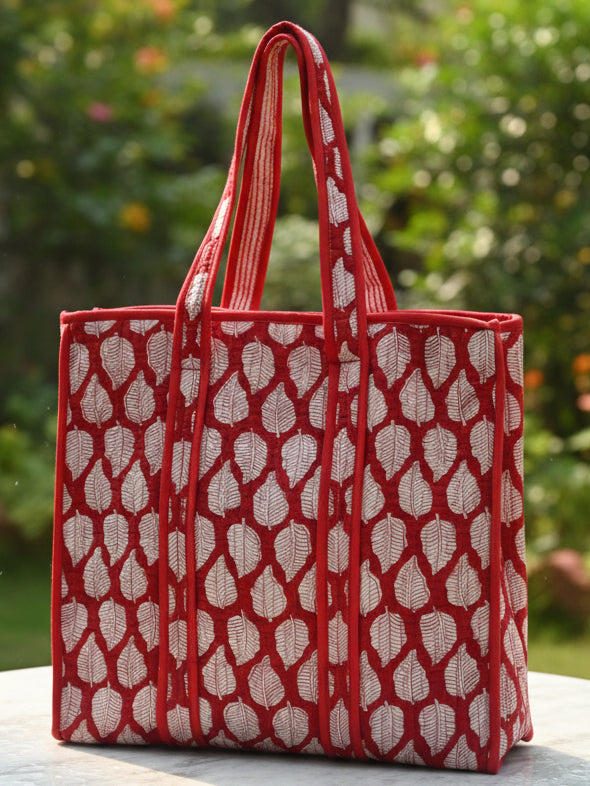 Red patterned bag on a surface with a floral-patterned fabric background