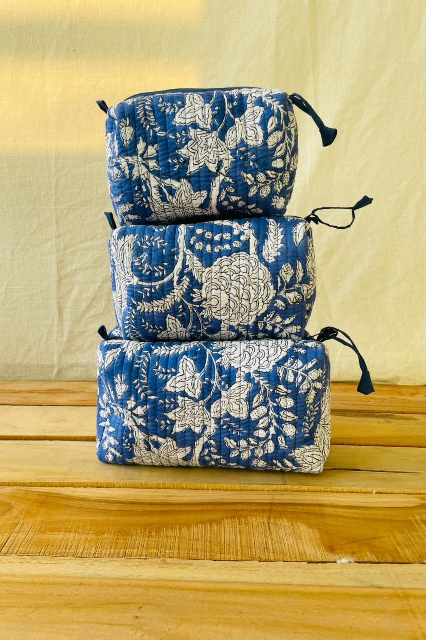 Stack of blue floral-patterned pouches on a wooden surface with a beige background
