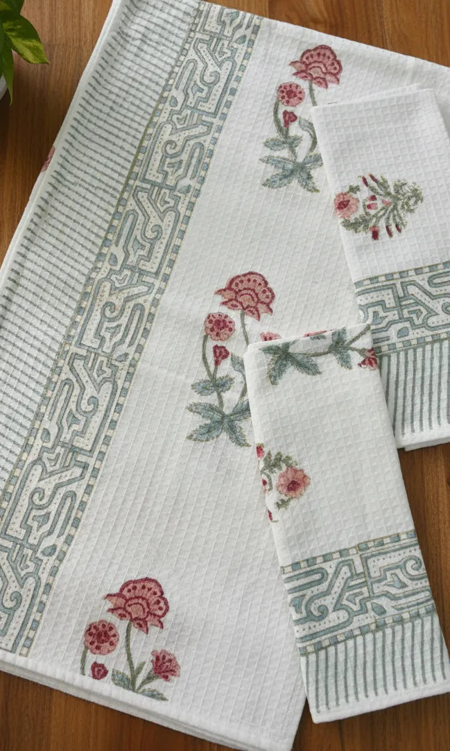 Set of white towels with floral and geometric patterns on a wooden surface