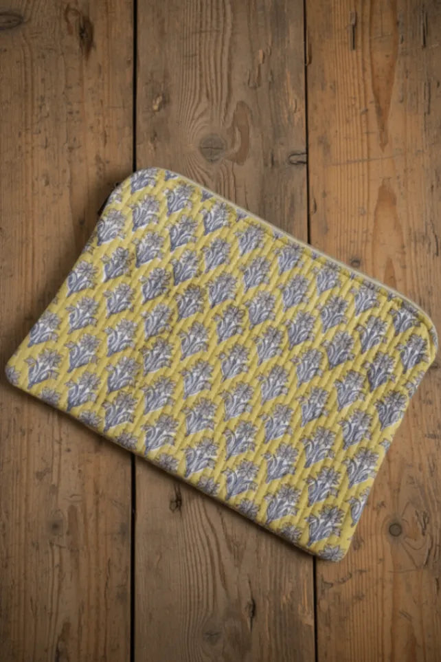 Yellow and gray patterned laptop sleeve on a wooden floor