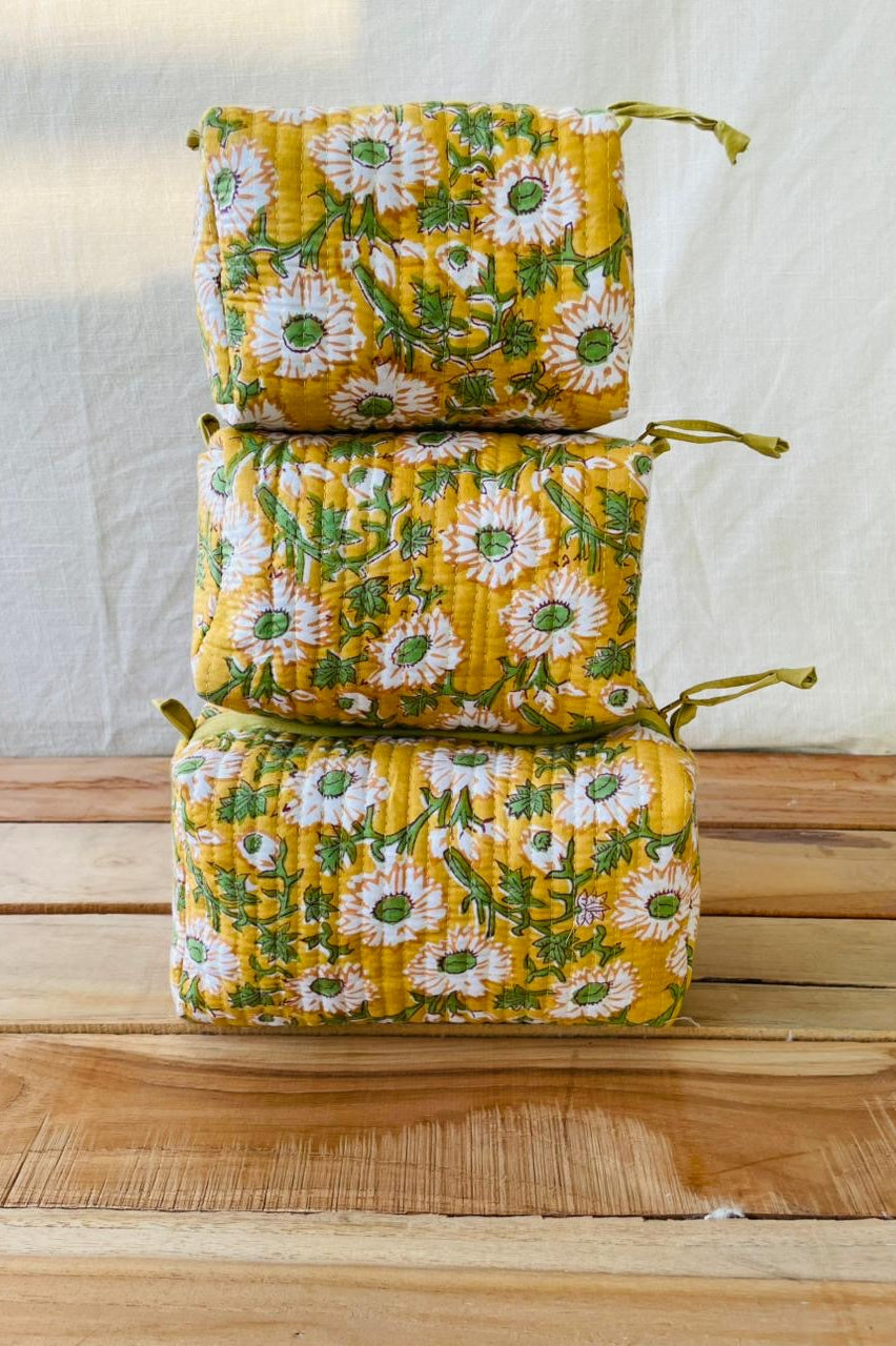 Stack of yellow floral fabric bags on a wooden surface with a white background