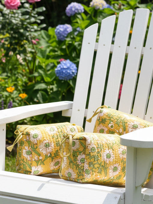 White wooden chair with yellow floral cushions in a garden setting