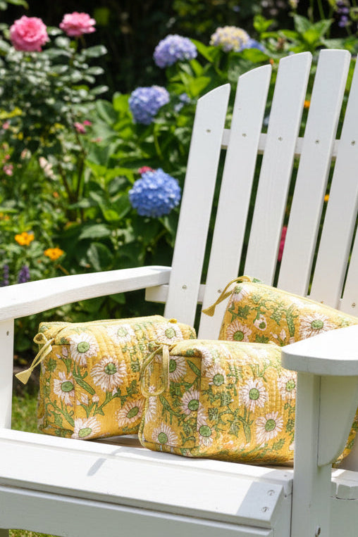 White wooden chair with yellow floral cushions in a garden setting