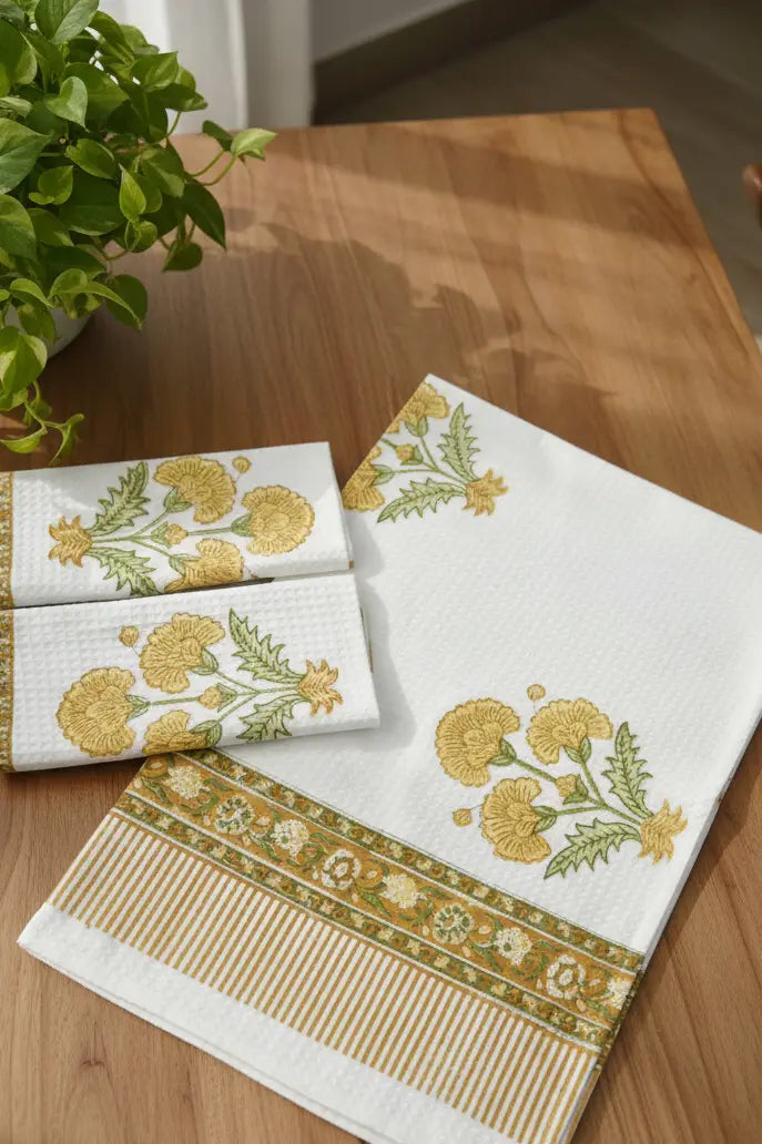 Set of embroidered towels on a wooden table with a plant in the background